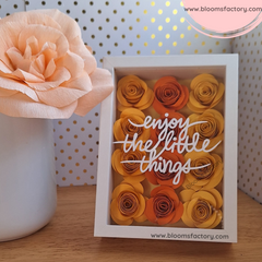 ¡Descubre la belleza en los detalles con este encantador cuadro decorativo! ‘Enjoy the Little Things’ está bellamente escrito entre flores de papel hechas a mano en tonos amarillos y naranjas creando una pieza que no solo es visualmente atractiva sino también inspiradora. Perfecto para añadir un toque de color y positividad a cualquier espacio. ¡Encuentra la alegría en los pequeños momentos! 