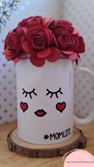 Taza decorativa coronada con flores de papel, la base está decorada con un rostro adorable de ojos tiernos y mejillas sonrosadas que te hará sonreír cada vez que la veas. 